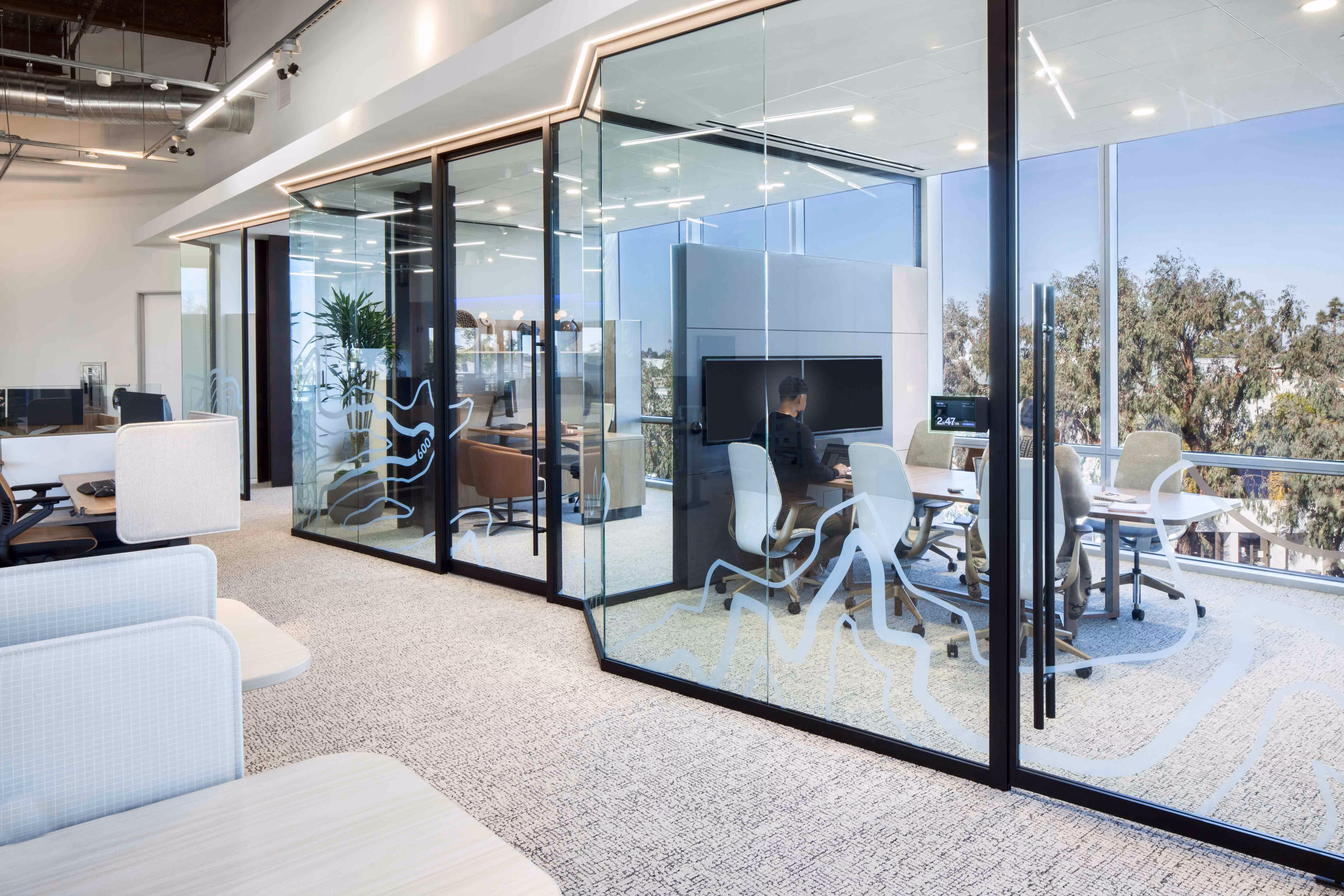 Private office design with framed glass wall, library and meeting room